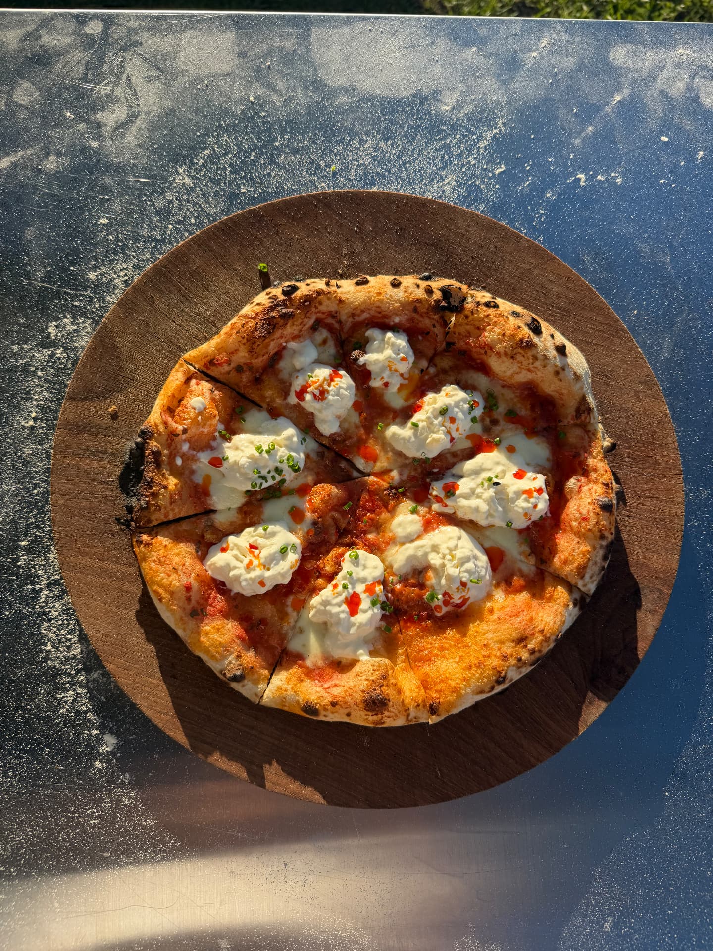 Sliced sourdough pizza with creamy cheese and herbs on a wooden board