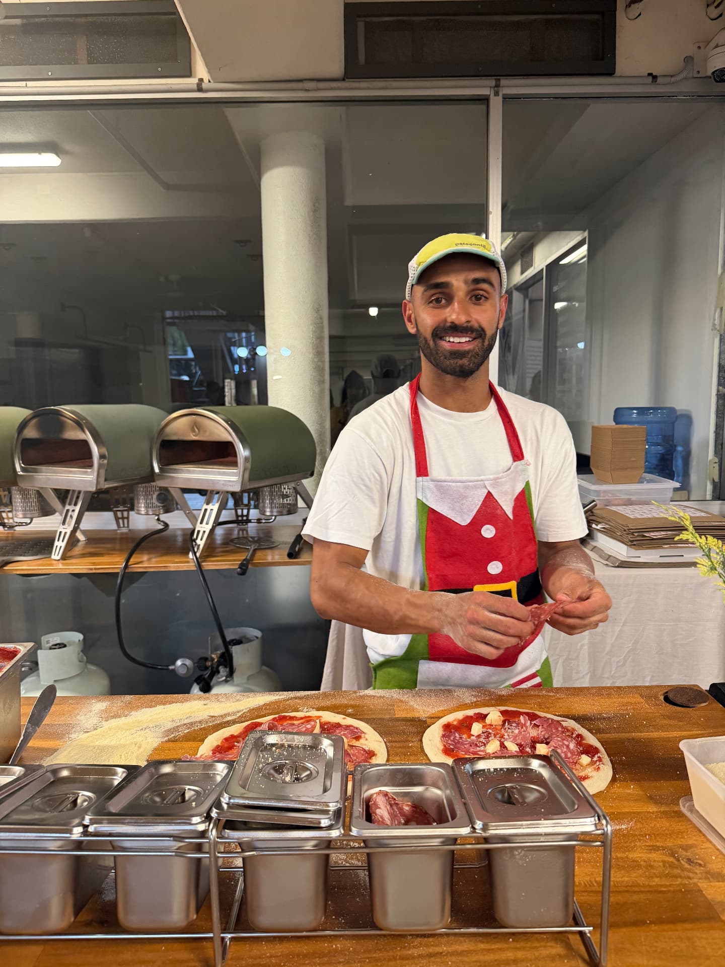Tribe Pizza founder in a red apron preparing pizzas at the bench
